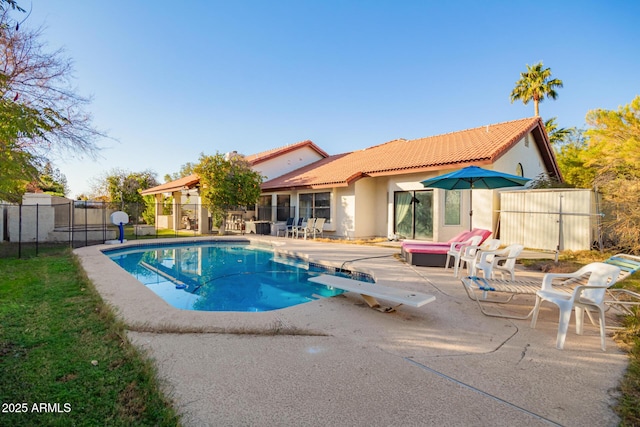 view of swimming pool with a patio area and a diving board