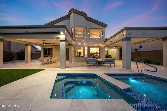 6435 E Monte Cristo Ave, Scottsdale, AZ 85254 - back of house at dusk featuring a ceiling fan, an in-ground hot tub, and a patio