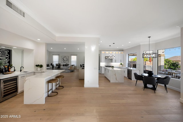 6435 E Monte Cristo Ave, Scottsdale, AZ 85254 - kitchen with wine cooler, a chandelier, open floor plan, white cabinets, and a breakfast bar