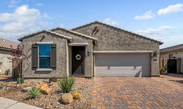view of front of home featuring stucco siding, a garage, decorative driveway, and a tiled roof