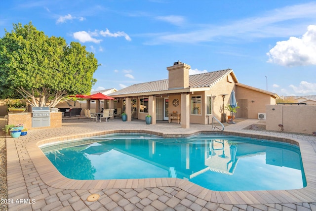 view of swimming pool featuring an outdoor kitchen, a patio, and grilling area