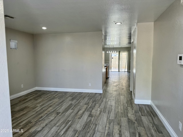 hall featuring dark wood-style floors, recessed lighting, visible vents, and baseboards