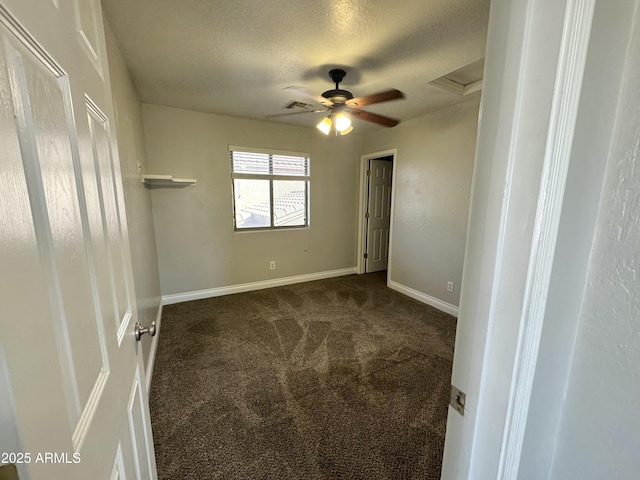 unfurnished bedroom featuring dark colored carpet, visible vents, attic access, a textured ceiling, and baseboards