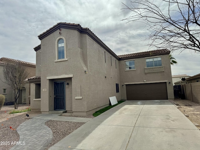 mediterranean / spanish home with driveway, a tiled roof, an attached garage, and stucco siding