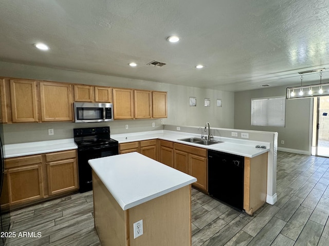 kitchen featuring wood finish floors, a sink, a peninsula, and black appliances