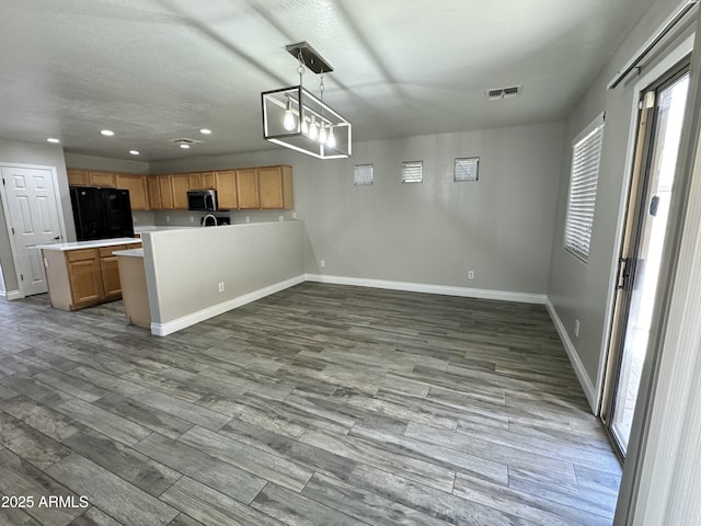 kitchen with visible vents, stainless steel microwave, wood finished floors, freestanding refrigerator, and light countertops