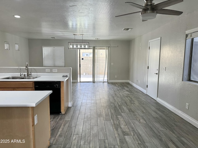 kitchen featuring a sink, wood finished floors, visible vents, light countertops, and dishwasher