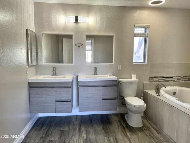 full bathroom with toilet, a garden tub, wood finished floors, and vanity