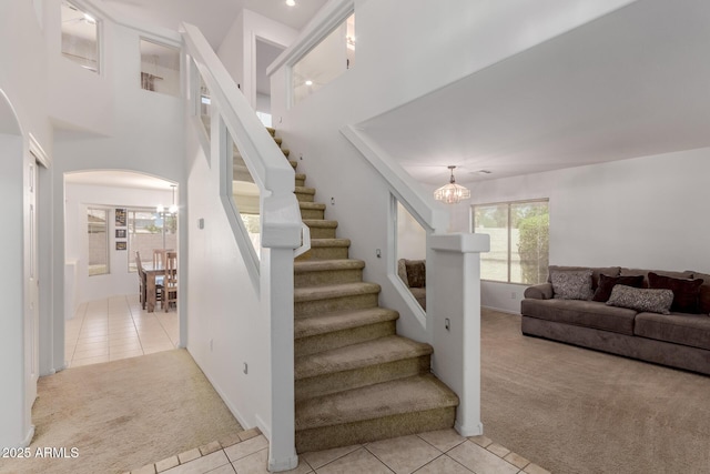 6276 N 75th Ln, Glendale, AZ 85303 - stairway featuring carpet, a chandelier, tile patterned flooring, and arched walkways