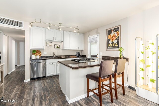 kitchen featuring white cabinets, sink, dark wood-type flooring, appliances with stainless steel finishes, and a breakfast bar area