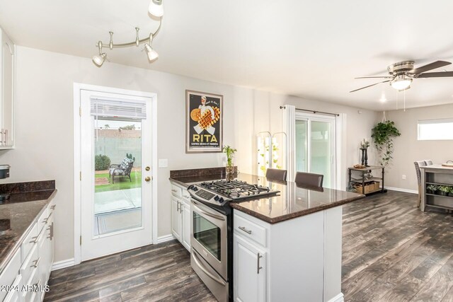 kitchen with dark stone countertops, dark wood-type flooring, white cabinets, ceiling fan, and stainless steel range with gas stovetop