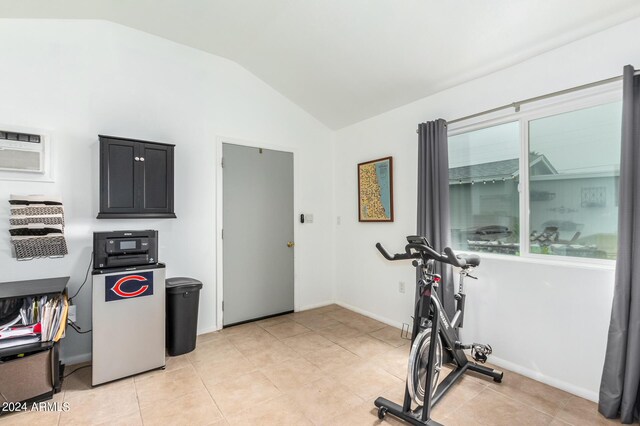 exercise room featuring vaulted ceiling and light tile patterned flooring