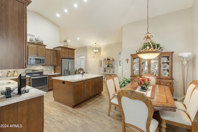 kitchen featuring pendant lighting, lofted ceiling, a kitchen island with sink, decorative backsplash, and appliances with stainless steel finishes