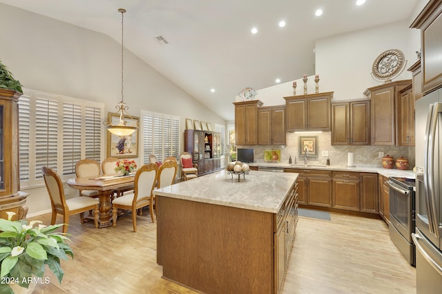 kitchen with decorative backsplash, appliances with stainless steel finishes, sink, pendant lighting, and a center island