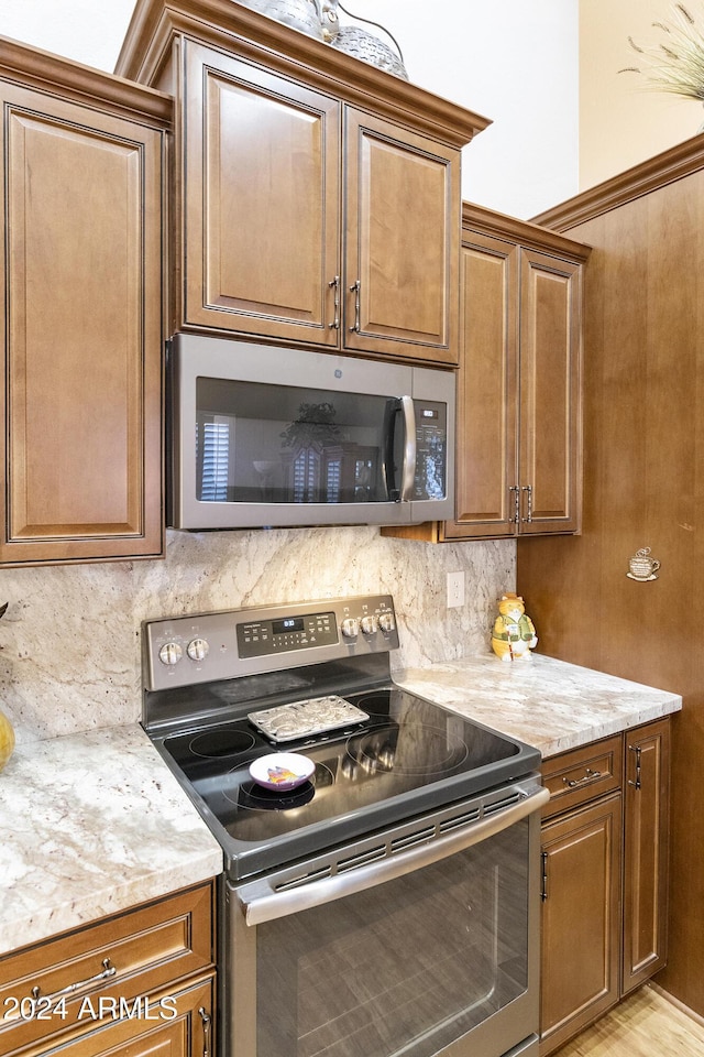 kitchen featuring light stone countertops, appliances with stainless steel finishes, and tasteful backsplash