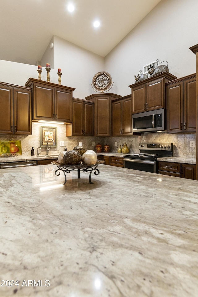 kitchen with dark brown cabinets, stainless steel appliances, and high vaulted ceiling