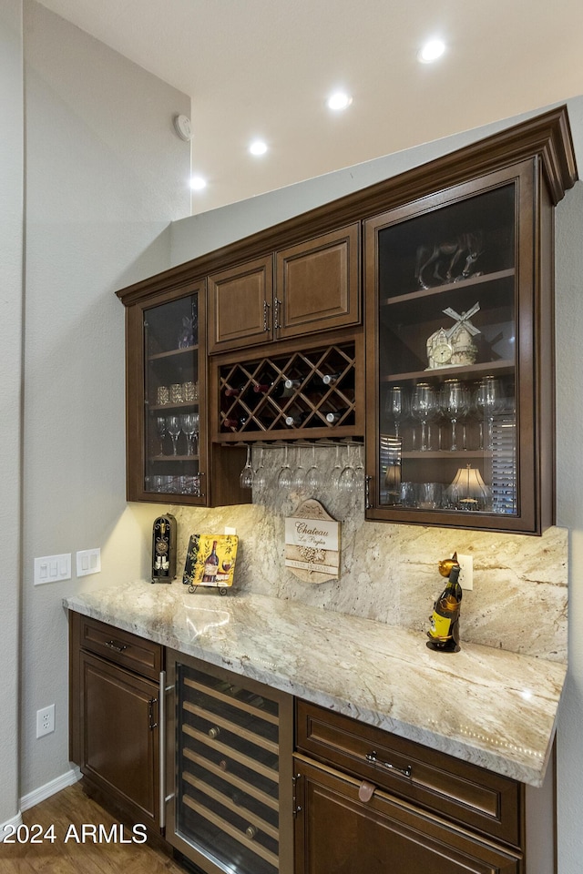 bar with tasteful backsplash, dark brown cabinets, and dark hardwood / wood-style floors