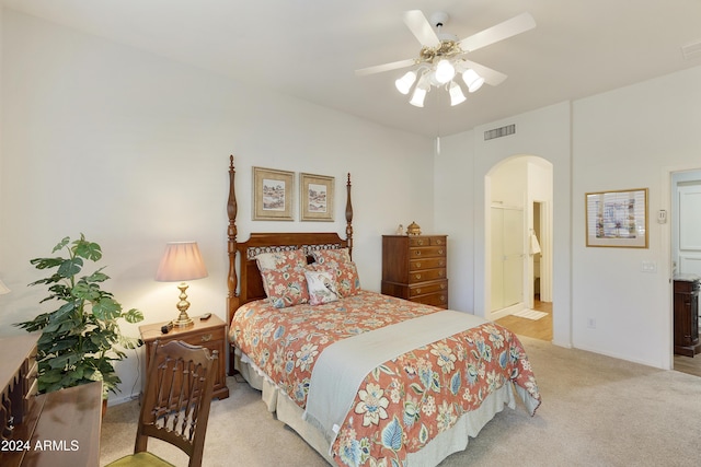 bedroom with connected bathroom, light colored carpet, and ceiling fan