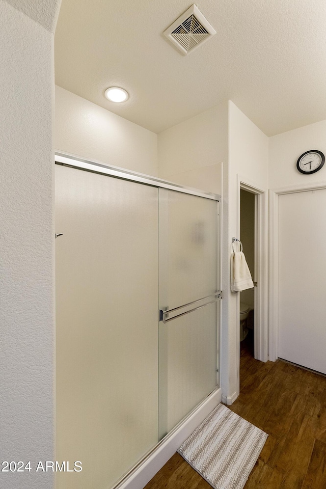 bathroom with hardwood / wood-style floors and a shower with door