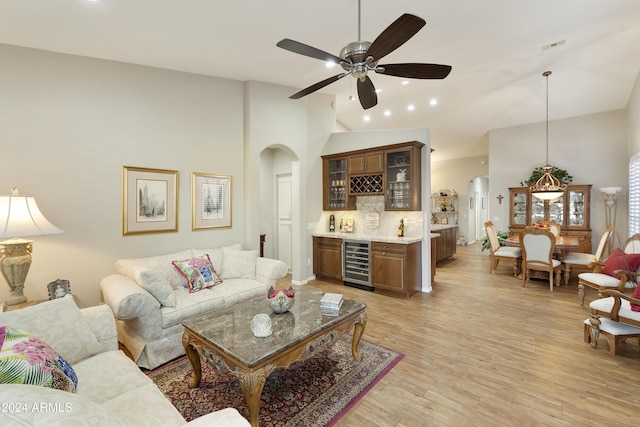 living room featuring ceiling fan, beverage cooler, bar area, light hardwood / wood-style floors, and lofted ceiling