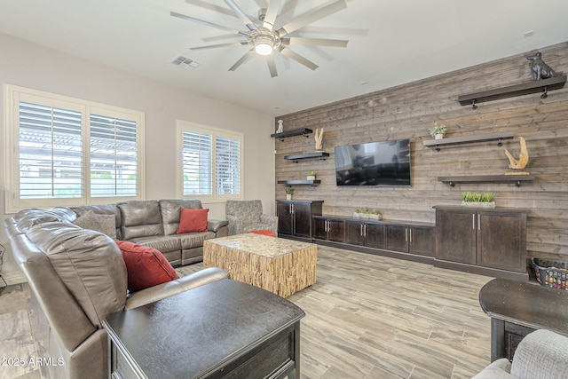 living area featuring visible vents, wood finished floors, wood walls, and a ceiling fan