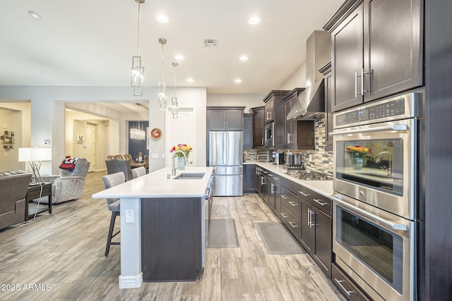 kitchen featuring visible vents, dark brown cabinets, open floor plan, appliances with stainless steel finishes, and a sink