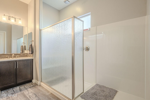 full bath with decorative backsplash, a stall shower, vanity, and wood finished floors