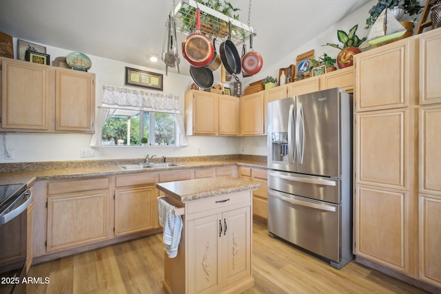 kitchen featuring sink, light brown cabinetry, appliances with stainless steel finishes, and lofted ceiling