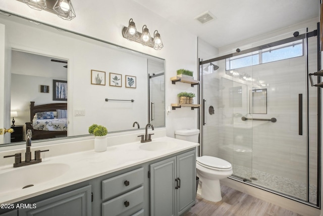 bathroom featuring hardwood / wood-style flooring, toilet, vanity, and a shower with door