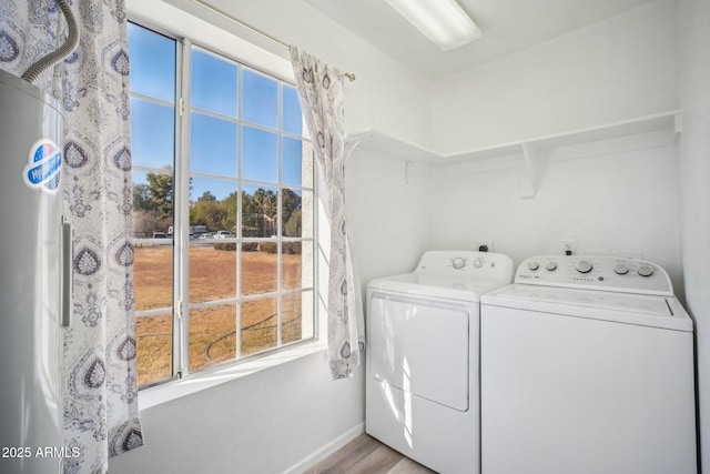 laundry room with light wood-type flooring, a healthy amount of sunlight, and washer and dryer