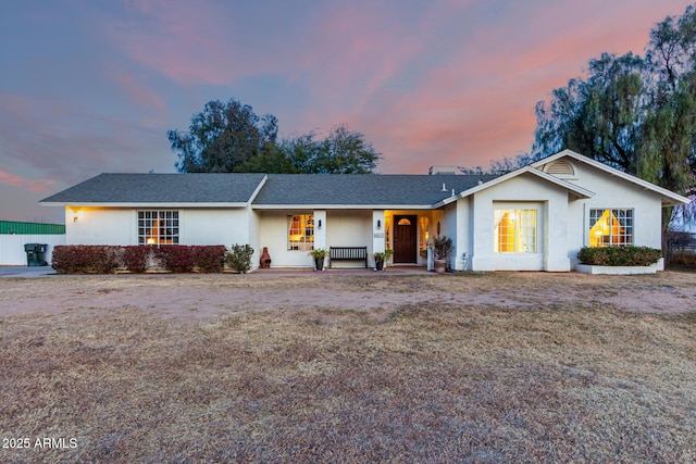 ranch-style house featuring a porch and a lawn