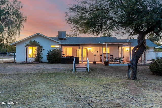 back house at dusk featuring central AC, a yard, and a patio