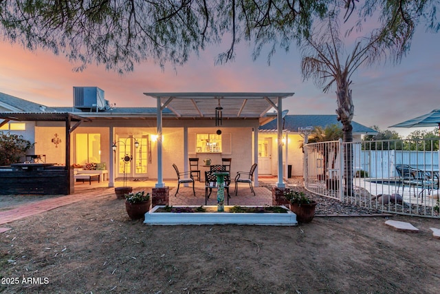 back house at dusk with cooling unit, a patio, and a pergola