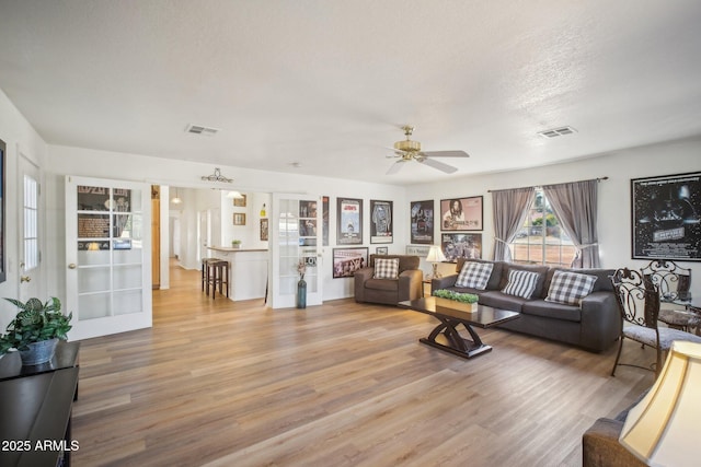 living room with ceiling fan, a textured ceiling, and hardwood / wood-style flooring