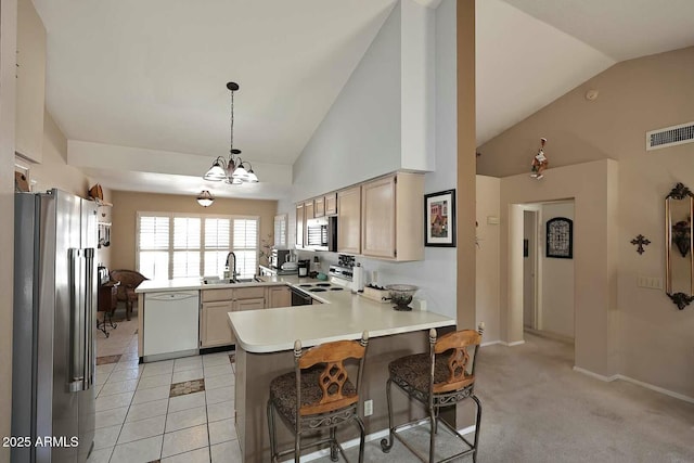 kitchen featuring kitchen peninsula, a kitchen breakfast bar, hanging light fixtures, appliances with stainless steel finishes, and sink