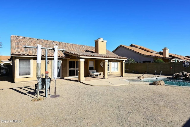 rear view of house with a patio area, a fenced in pool, and pool water feature