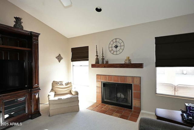 living room with a tiled fireplace, carpet flooring, and lofted ceiling