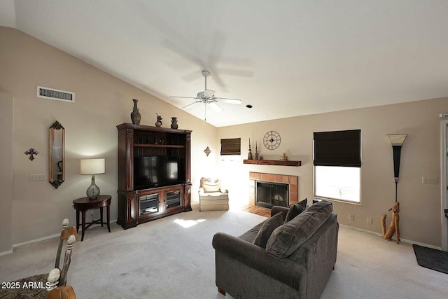 carpeted living room featuring ceiling fan, a tile fireplace, and lofted ceiling