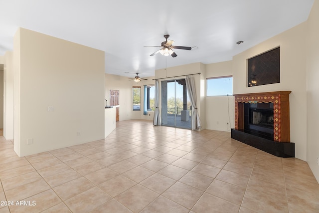 unfurnished living room featuring a fireplace, ceiling fan, and light tile patterned flooring