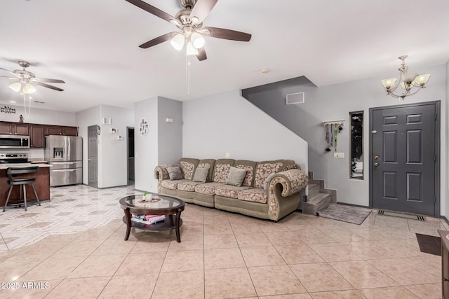 tiled living room with ceiling fan with notable chandelier