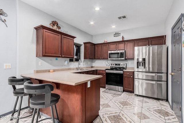 kitchen with appliances with stainless steel finishes, a kitchen breakfast bar, kitchen peninsula, and sink