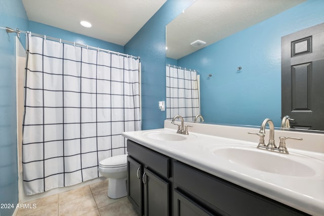 bathroom with toilet, a textured ceiling, vanity, and tile patterned floors