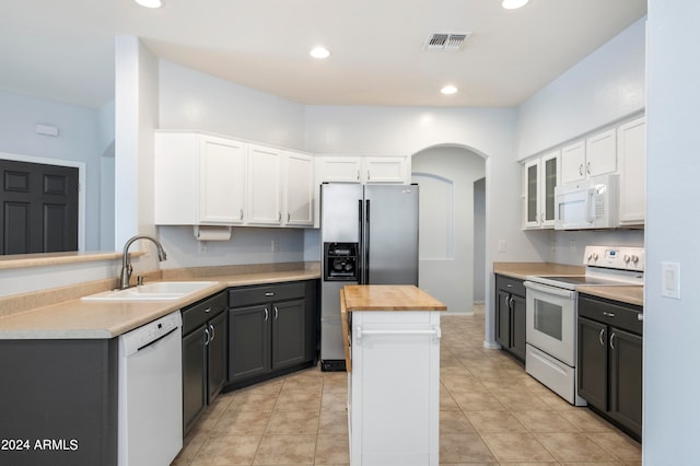 kitchen with white appliances, white cabinets, sink, a center island, and wooden counters