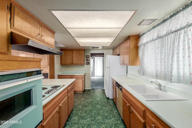 kitchen with dark floors, under cabinet range hood, light countertops, white appliances, and a sink