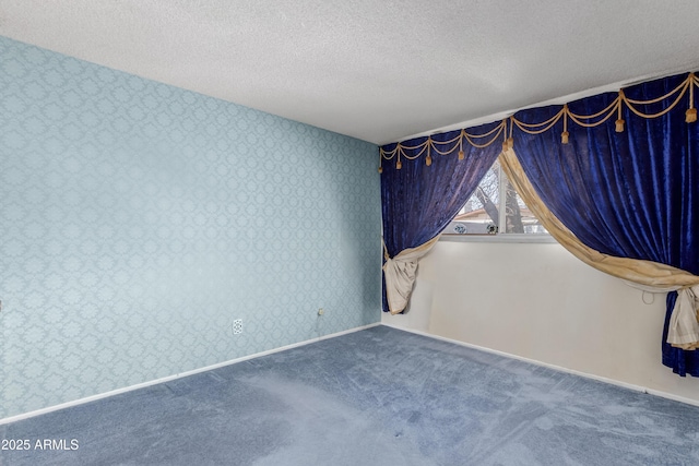 spare room with baseboards, a textured ceiling, wallpapered walls, and carpet