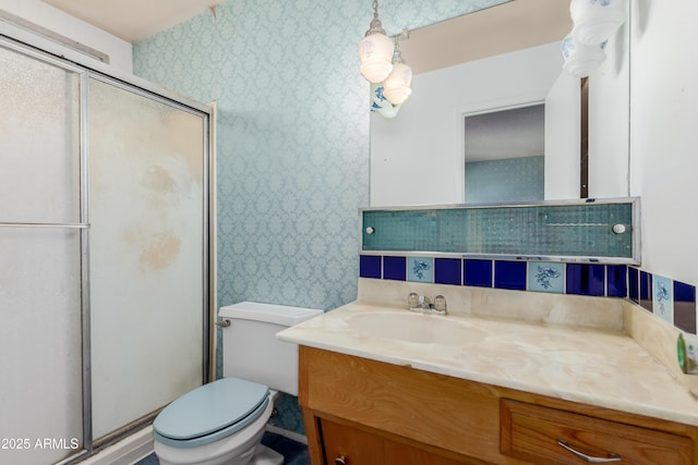 full bath with a shower stall, wallpapered walls, vanity, and toilet