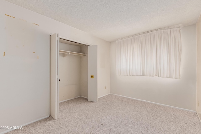 unfurnished bedroom featuring a closet, carpet flooring, a textured ceiling, and baseboards