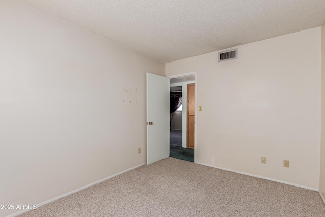 unfurnished room featuring carpet flooring, baseboards, visible vents, and a textured ceiling