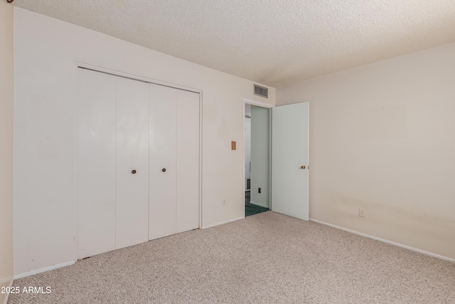 unfurnished bedroom with a closet, visible vents, carpet floors, and a textured ceiling