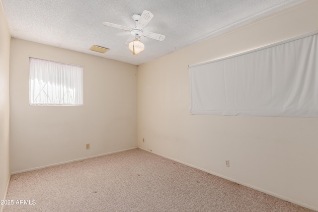 unfurnished room featuring visible vents, a ceiling fan, a textured ceiling, carpet, and baseboards